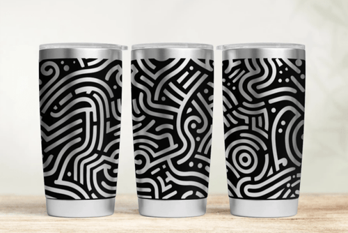 Three tumblers with black and white patterned design on a wooden surface.
