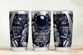 Three tumblers with astronaut design and text on a wooden surface.