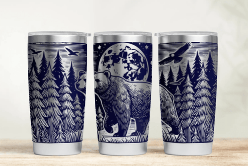 Three tumblers with nature-themed designs on a wooden surface.