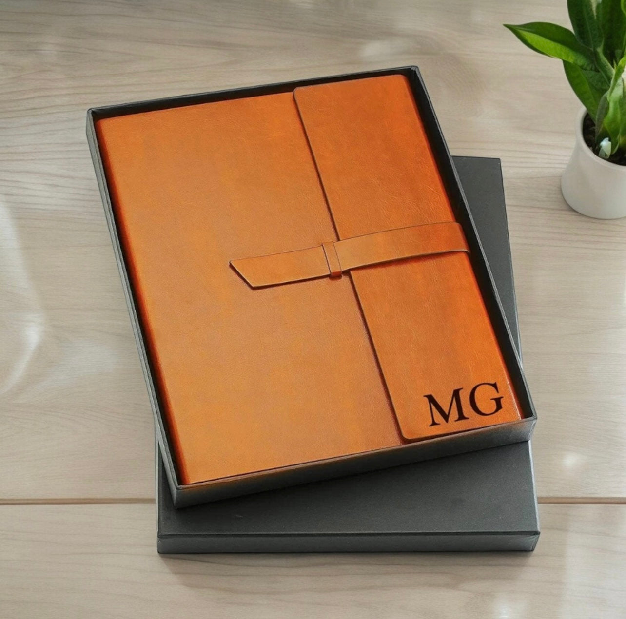 Orange leather-bound book with 'MG' initials in a black box on a wooden surface.