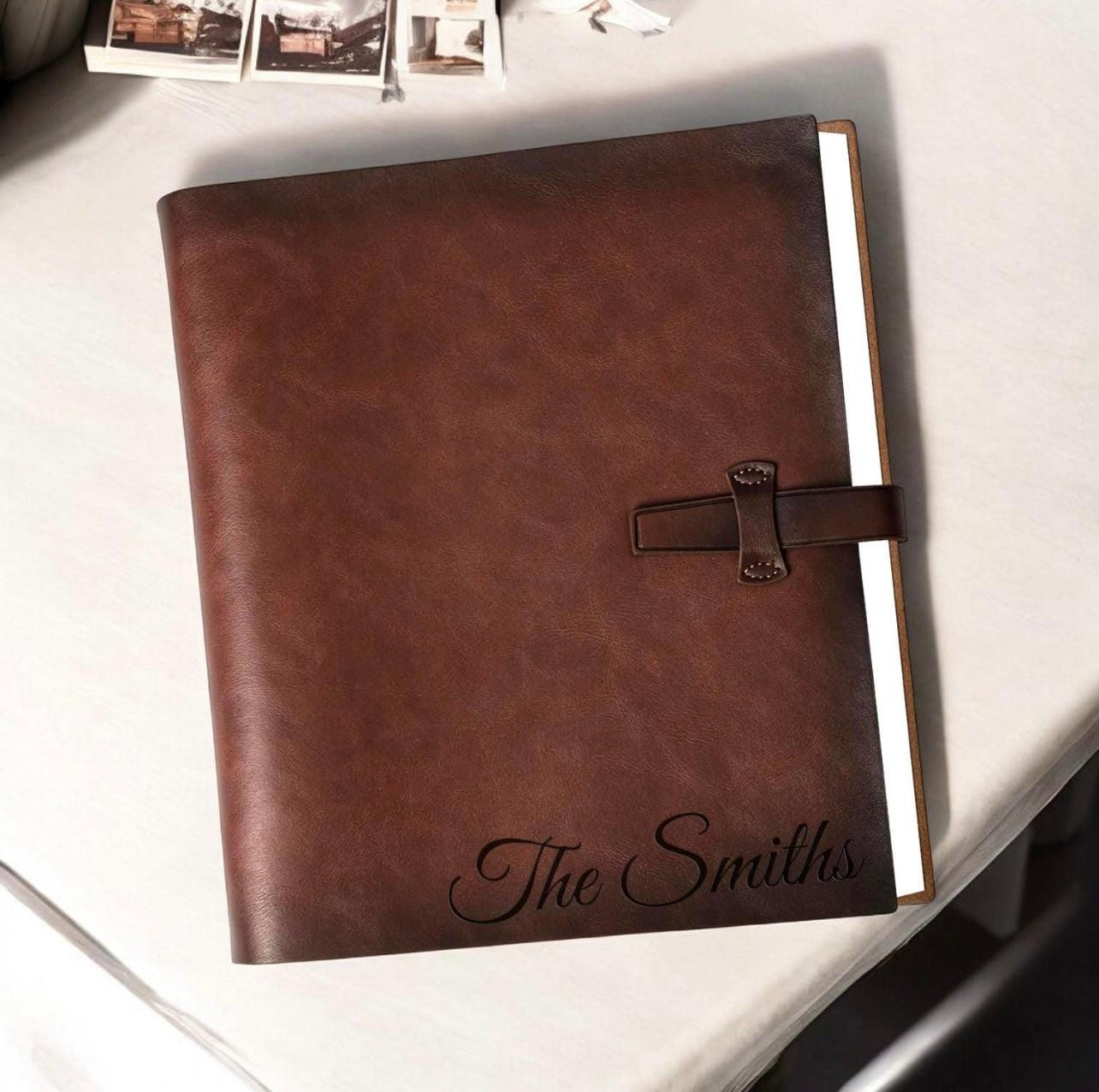 Brown leather photo album with 'The Smiths' engraving on a light surface.