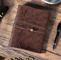Brown leather notebook with 'Michael' engraving on a wooden surface with a pen.