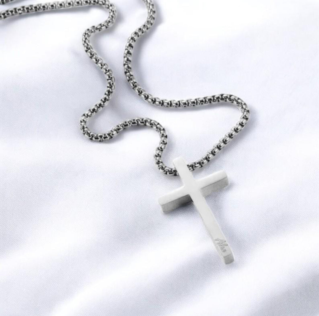 White cross pendant on a chain against a white background