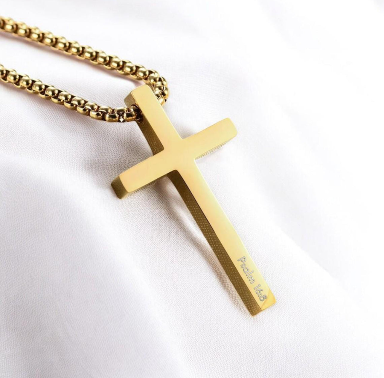 Gold cross pendant on a chain against a white background