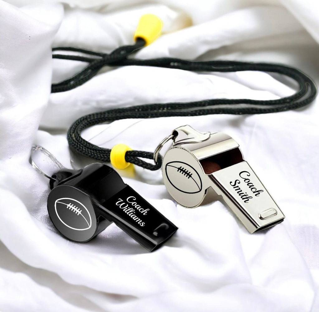 Two whistles with 'Coach Smith' and 'Coach Williams' engraved on them, attached to black lanyards.