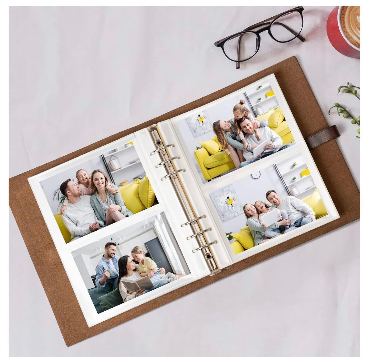Open photo album with family photos on a light surface, with glasses and a cup in the background.