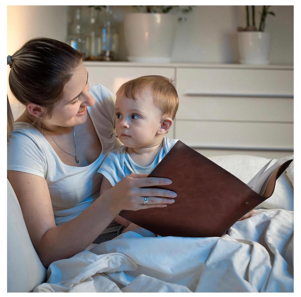 Woman and child reading a book together on a couch in a cozy living room.