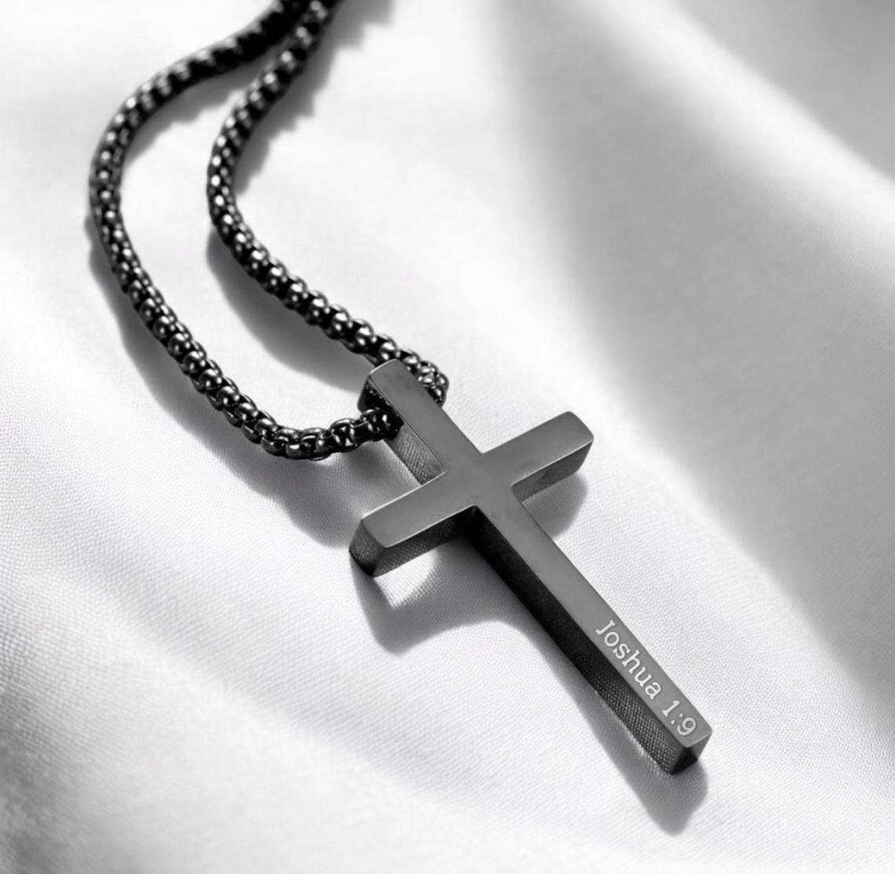 Black cross pendant necklace on a white background