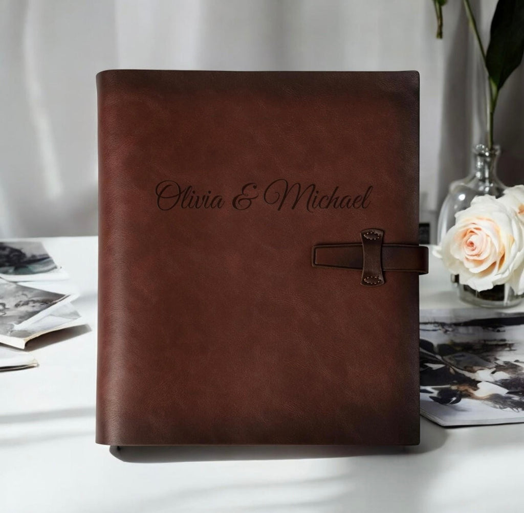 Brown leather album with 'Olivia & Michael' embossed on it, placed on a white surface with a blurred background.