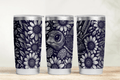 Three tumblers with floral and nature-themed designs on a wooden surface.